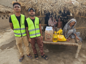 Two volunteers with donation supplies outside hut.